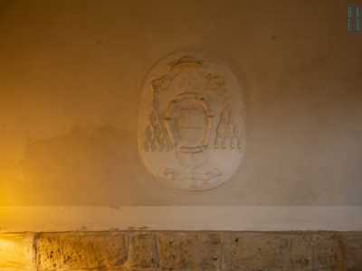 Sulla parete attira la nostra attenzione un bianco stemma ecclesiastico in gesso con nappe, croci e un libro aperto al centro. �Ci � stato donato dalle suore, era l�emblema dell�arcivescovo che qui risiedeva�, precisa Alfredo